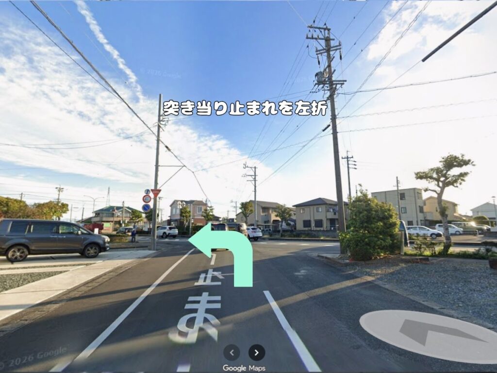 トリミングサロン「ドッグアシル」からの帰り道案内。「突き当り止まれを左折」のテロップが入り、路面に「止まれ」と書かれたT字路交差点をミントグリーンの矢印に従って左折する風景写真。