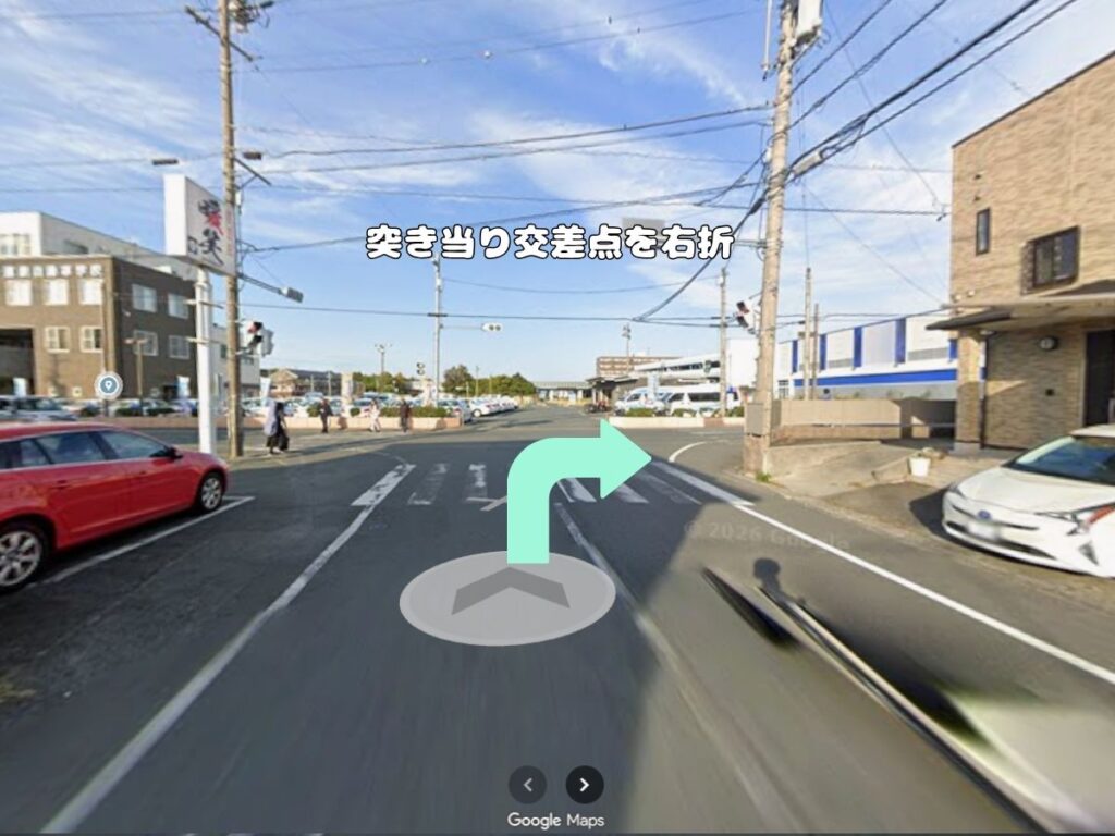 トリミングサロン「ドッグアシル」からの帰り道案内。「突き当り交差点を右折」のテロップが入り、開けた大通りの交差点をミントグリーンの矢印に従って右折する風景写真。