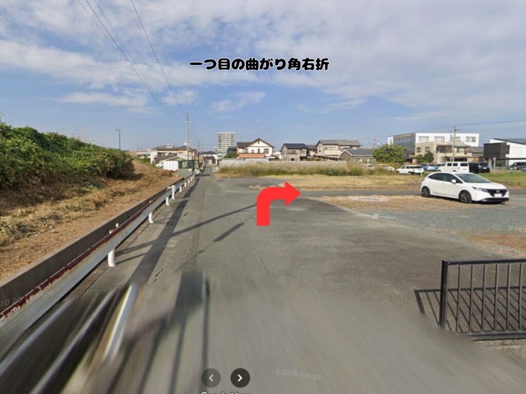 トリミングサロン「ドッグアシル」へのアクセス案内。高架下を通過した直後、すぐ右手に見える「一つ目の曲がり角右折」を赤い矢印で示した道路の風景写真。