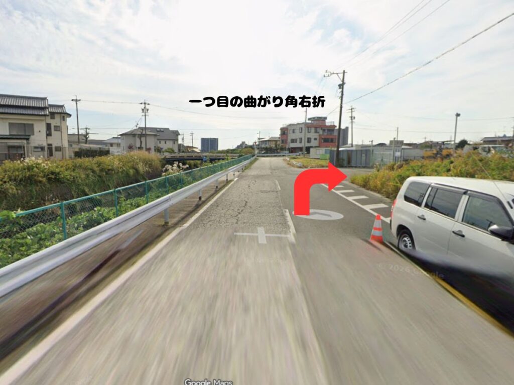 トリミングサロン「ドッグアシル」へのアクセス案内。1つ目の角を左折した直後、すぐ右手にある「一つ目の曲がり角右折」を赤い矢印で示した道路の風景写真。